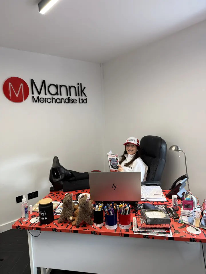 Arlene relaxing at her desk under the Mannik logo